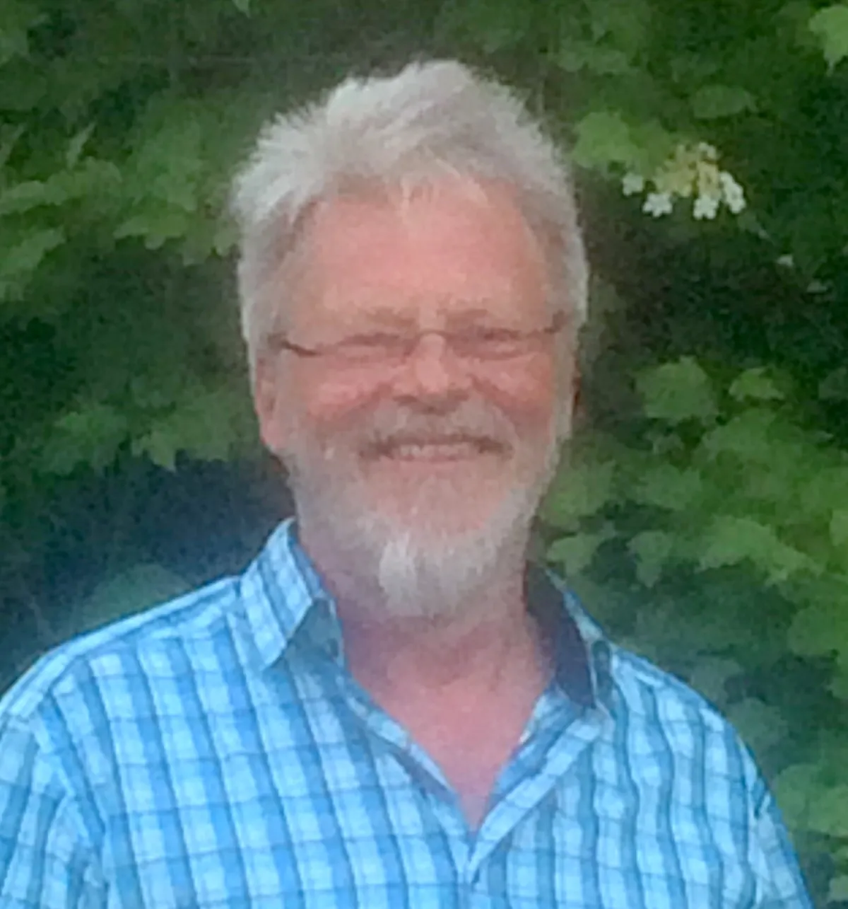 Jörg Pantel, Heilpraktiker in Münster, lächelnd vor Grün