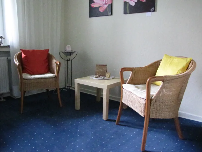 Sitzecke im Praxisraum mit zwei Korbsesseln und einem kleinen Tisch
