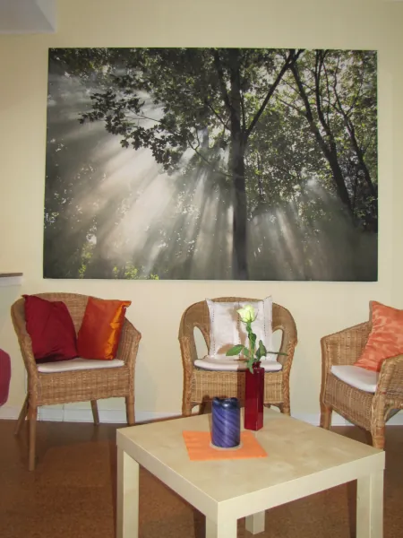Wartebereich mit Korbstühlen und einem großen Waldbild an der Wand